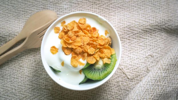 Corn flakes, cereal and milk splash in bowl. Natural homemade plain organic yogurt in wood bowl on wood texture background