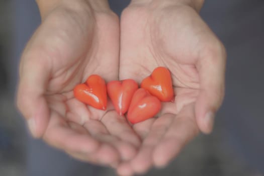 Red glass hearts in man hands. Caring concept idea. Valentine’s Day and health, medicine and charity concept background