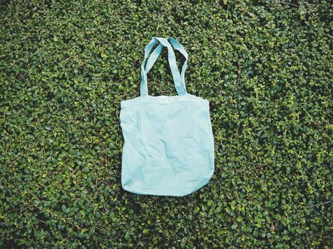 Blank blue Mockup Linen Cotton Tote Bag on Green Bush Trees Foliage Background. Eco Nature Friendly Style. Environmental Conservation Recycling Concept. Template for Artwork Text. Japanese