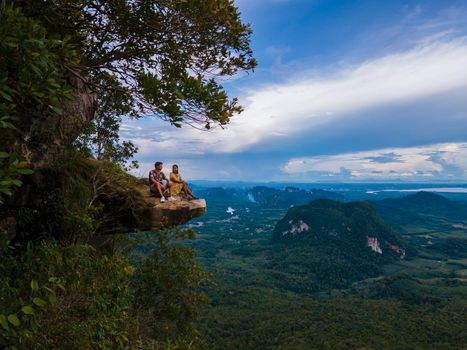 Dragon Crest mountain Krabi Thailand, a Young traveler sits on a rock that overhangs the abyss, with a beautiful landscape. Dragon Crest or Khuan Sai at Khao Ngon Nak Nature Trail in Krabi, Thailand