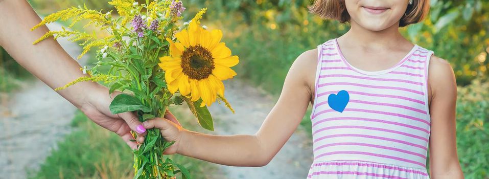 child holds a bouquet of wildflowers in his hands. Selective focus.