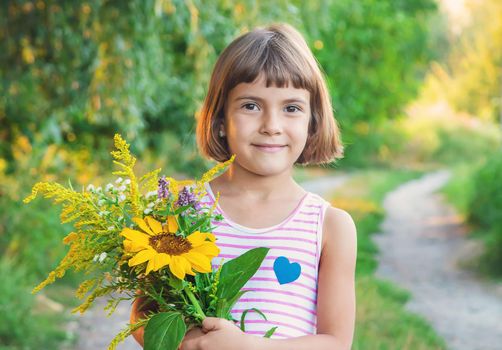 child holds a bouquet of wildflowers in his hands. Selective focus.