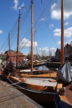 Old historical wooden fishing boats moored behind each other.  These are traditional Dutch botter boats. It's a bright sunny day in Bunschoten-Spakenburg, the Netherlands. This town was in the past an important fisher harbor when the inland sea IJsselmeer was still direct connected with the North sea.