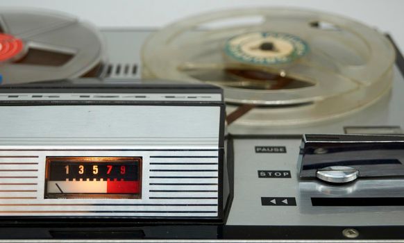 A vintage reel-to-reel tape recorder with a vu meter and a large switch from the seventies 