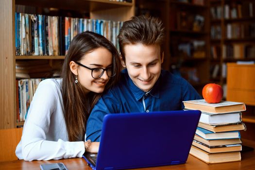 Male and female student preparing for classes in library together