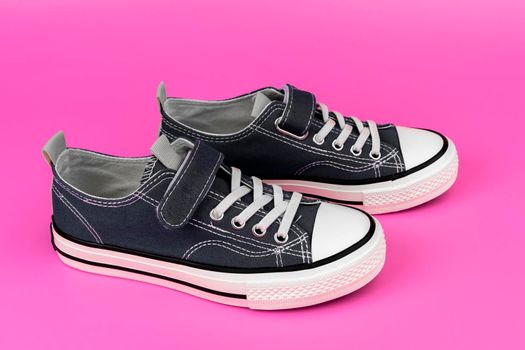 a pair of blue sneakers on a pink background. Classic athletic shoes. Fashionable youth shoes. side view from above. copy space