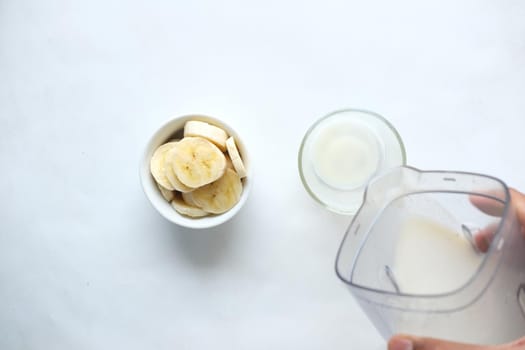 close up of slice of banana glass of milk on table .