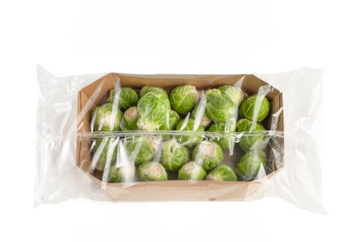 Isolate of fresh Brussels sprouts in paper wrapping and a transparent plastic bag. Brussels sprouts in transparent packaging from the store on a white background