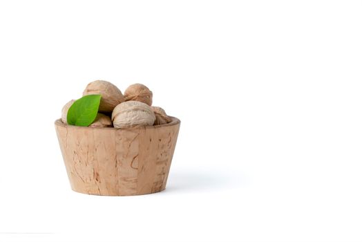 Walnut. Walnut fruits of different varieties lie in wooden saucers and baskets on a white isolated background. Nearby are green leaves and unripe walnut fruits