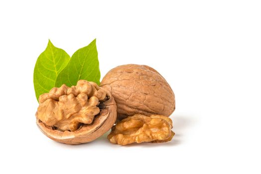Walnut fruits lie on a white isolated background. Peeled walnut and green leaves with shadow. White isolate for design and project insertion.
