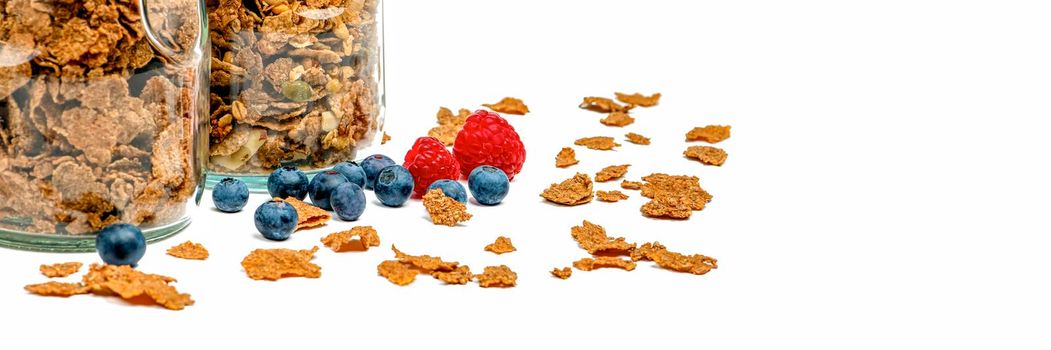 Isolate muesli. Dry muesli flakes with raspberries and blueberries lie on an isolated white background. Breakfast cereals in a glass jar on a white background