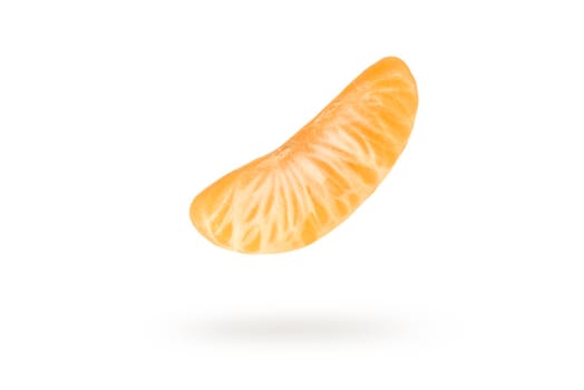 A piece of mandarin isolated on a white background, falling casting a shadow. Individual segments of tangerine slices, for inserting into a project or design