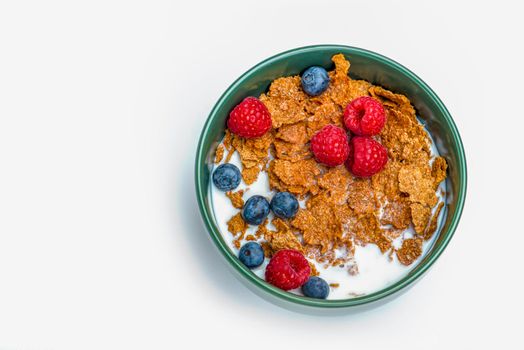 Muesli, isolate on white. Breakfast, healthy food and diet. Muesli with fruits and milk in a plate. Blueberries, strawberries and raspberries on a background of muesli flakes.