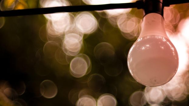 Beautiful retro bulb light lamp decor. Hanging decorative Christmas lights for an outdoor party. Blur bokeh background