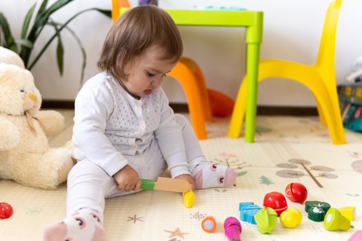 happy funny kid curly baby girl with educational toy blocks flowers. Children play at day care or preschool. Mess in kids room. Toddler build tower in kindergarten. Child playing with colorful toys.