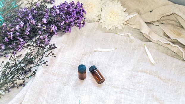 Bottle of essential oil. Herbal medicine or aromatherapy dropper bottle isolated on white background. Fresh rosemary flowers and essential oils on the table