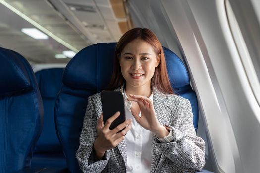 Portrait attractive asian woman use of mobile phone on airplane, looking at camera