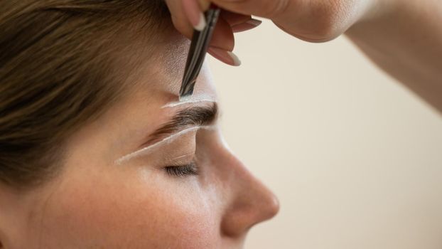 The master draws the shape of the eyebrows with white paint before coloring