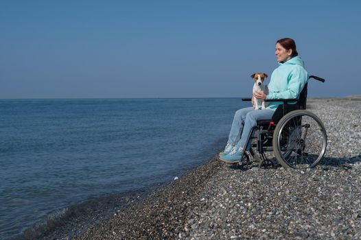 Caucasian woman in a wheelchair with a dog at the sea