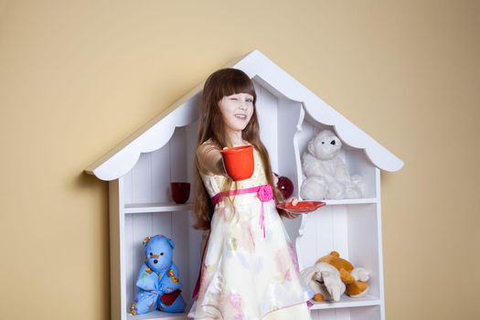 Happy little girl with cup of tea in her room. drinking and happy. studio shot.