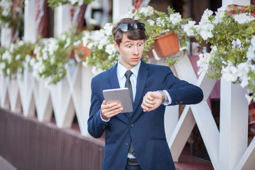 young man in business suit holding tablet on summertime day.