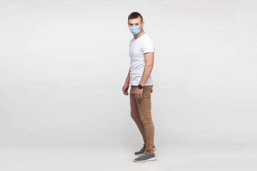 Protection against contagious disease, coronavirus. full length portrait of young man wearing hygienic mask to prevent infection, Covid-2019. indoor studio shot isolated on gray background