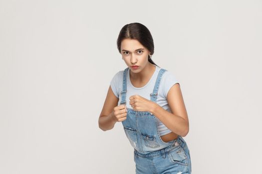 Boxing. Young adult indian woman, ready for fight on gray background.