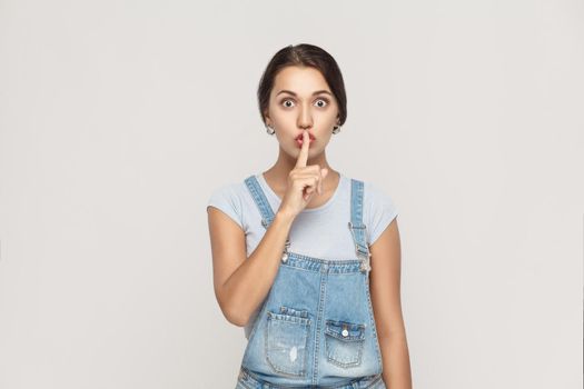 Shh sign. Beautiful indian woman looking at camera with silent sign. Studio shot, on gray background.