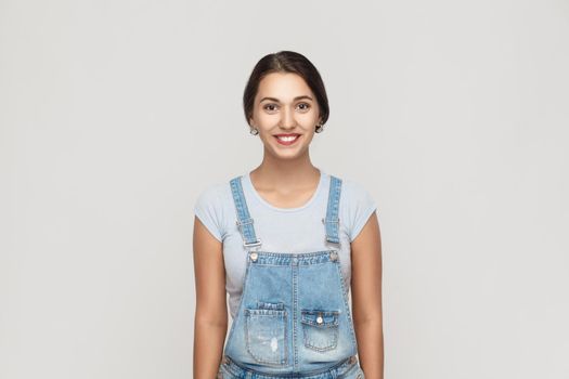 Beauty concept. The attractive brown haired young adult latin woman with perfect clean skin looking and smiling at camera. Isolated studio shot on gray background