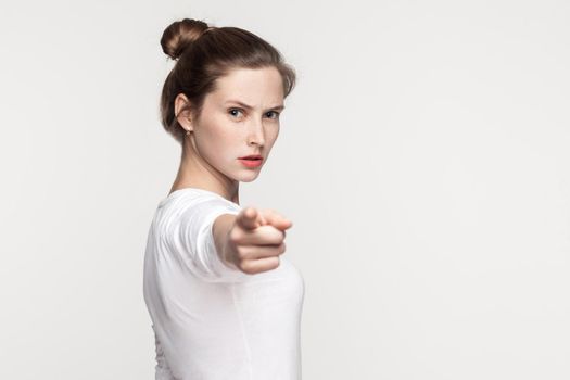 Hey you! Freckles woman pointing finger at camera. Studio shot