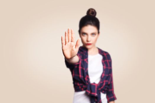 Young annoyed woman with bad attitude making stop gesture with her palm outward, saying no, expressing denial or restriction. Negative human emotions, feelings, body language. Selective focus on hand.