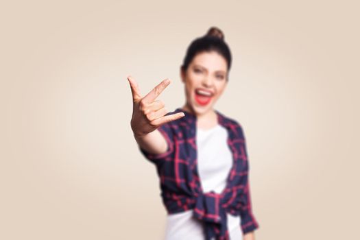 Rock sign. Happy funny toothy smiley young woman showing Rock sign with fingers. studio shot on beige background. focus on fingers.
