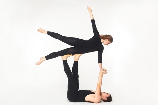 Acroyoga concept, fly pose. Young man holding woman and balancing. Studio shot, isolated on white background