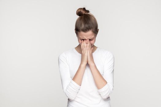 Dramatic young girl crossed hands and cry. Studio shot,isolated on gray background