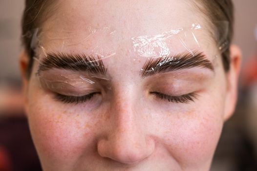 Caucasian woman on the procedure of permanent styling and coloring of eyebrows