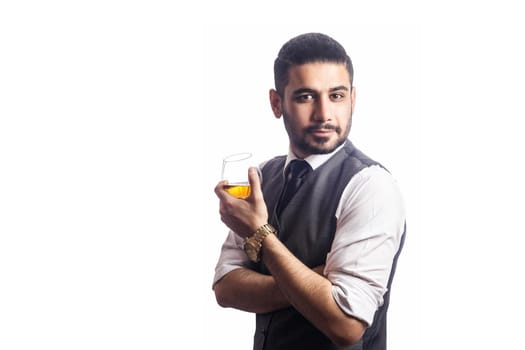 Handsome bearded businessman holding a glass of whiskey. holding glass and looking at camera. studio shot, isolated on white background.