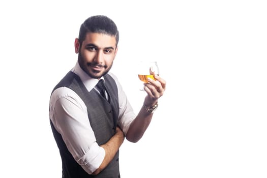 Handsome bearded businessman holding a glass of whiskey. holding glass and looking at camera with smile. studio shot, isolated on white background.