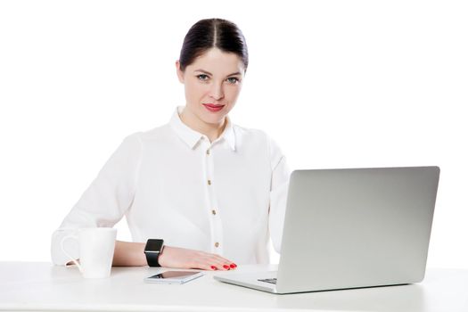Portrait of successful calm attractive brunette businesswoman with makeup in white shirt sitting with laptop and looking at camera with smile. indoor studio shot, isolated in white background.