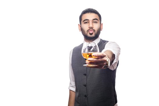 Handsome bearded businessman holding a glass of whiskey. share drink and send kiss. studio shot, isolated on white background.