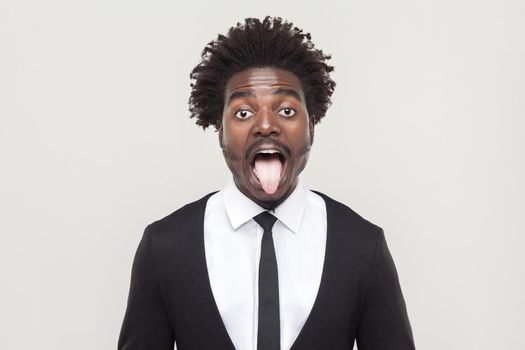 Crazy afro man looking at camera and tongue out. Studio shot, gray background