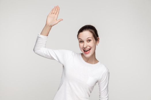 Hi! How are you? Happiness woman showing hello sign. Studio shot, gray background