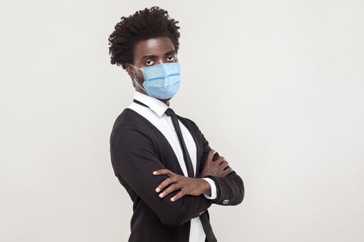 Protection against coronavirus. Alone man wearing hygienic mask to prevent infection, Covid-19. folded arms and looking at camera with sad worry face. indoor studio shot isolated on gray background