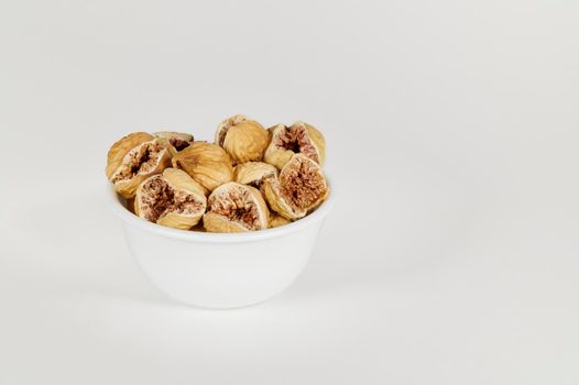 Closeup view of a bowl of dried figs on a white background