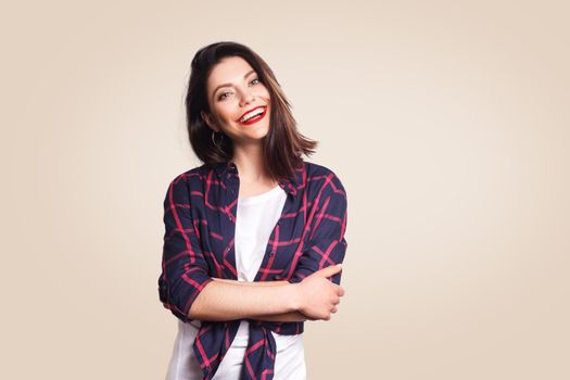 Portrait of beautiful happy girl in casual style looking at camera with toothy smile. studio shot on beige background.