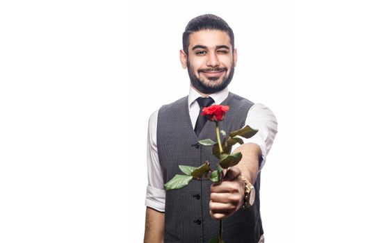 Handsome romantic happy man with rose flower. studio shot. isolated on white background. holding and giving flower and looking at camera and smiling with wink..