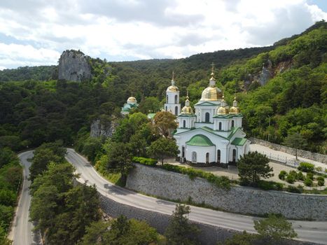 Christian church on a background of mountains. Temple of the Holy Archangel Michael in Oreanda. The southern coast of Crimea. Located on a rocky cliff and is surrounded by beautiful vegetation