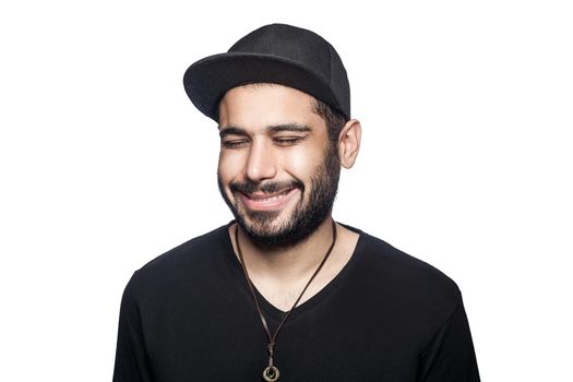 Portrait of young happy smilely man with black t-shirt and cap with closed eyes and toothy smile. studio shot, isolated on white background.