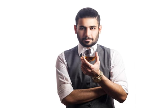 Handsome bearded businessman holding a glass of whiskey. holding glass and looking at camera. studio shot, isolated on white background.