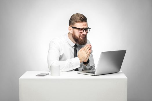 I need your help! Portrait of hopeful bearded young manager in white shirt and black tie are sitting in office and talking with friend thought skype and pleased for helping him in work task. Isolated