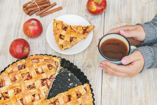 Girl with a cup of tea and a pie with apples and cinnamon. Selective focus. food.